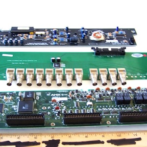 May include: Close-up of three circuit boards with various electronic components. The top board is black with green text, the middle board is green with multiple silver connectors, and the bottom board is green with black connectors.