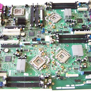 May include: Two green computer motherboards with various electronic components. They feature processors, RAM slots, and connectors. The boards have silver heat sinks, black and purple connectors, and numerous small capacitors and resistors.