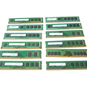 Könnte beinhalten: Eine Ansammlung grüner RAM-Speichermodule, angeordnet auf einer weißen Oberfläche. Jedes Modul hat eine rechteckige Form mit schwarzen Komponenten und weißen Etiketten. Die Module sind für Computerhardware bestimmt.