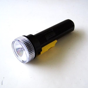 May include: A black flashlight with a clear lens and a yellow tape detail.
