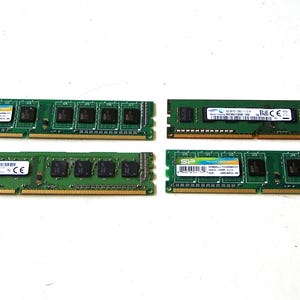 May include: Four green computer RAM sticks with black chips and labels are arranged on a white surface. The RAM sticks are rectangular and have gold-colored connectors along the bottom edge. The labels have text and barcodes.