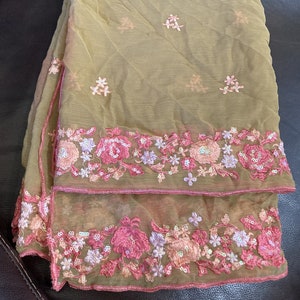 May include: A sheer green scarf with pink floral embroidery and sequins around the edges.