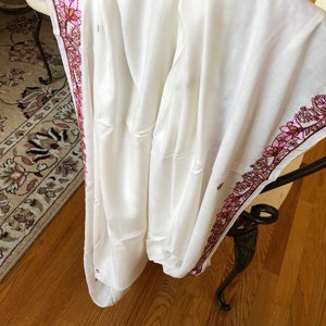 May include: White cotton shawl with a pink and burgundy floral embroidered border.