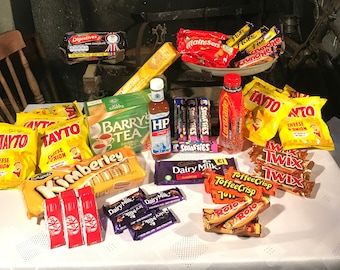 May include: A table top filled with a variety of popular British and Irish snacks, including chocolate bars, biscuits, crisps, and candy.  The brands include Dairy Milk, Twix, Toffee Crisp, Maltesers, and Tayto.