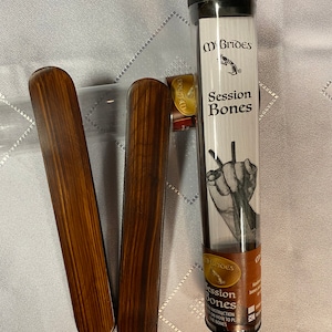 May include: Two brown wooden rhythm sticks, also known as "Session Bones", in a clear plastic tube with a white label that says "McBrides Session Bones".