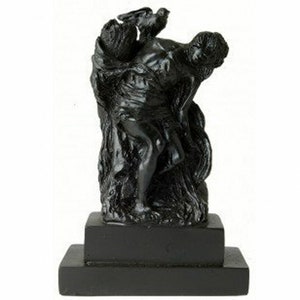 May include: Black and white sculpture of a person holding a bird. The sculpture is on a black pedestal.