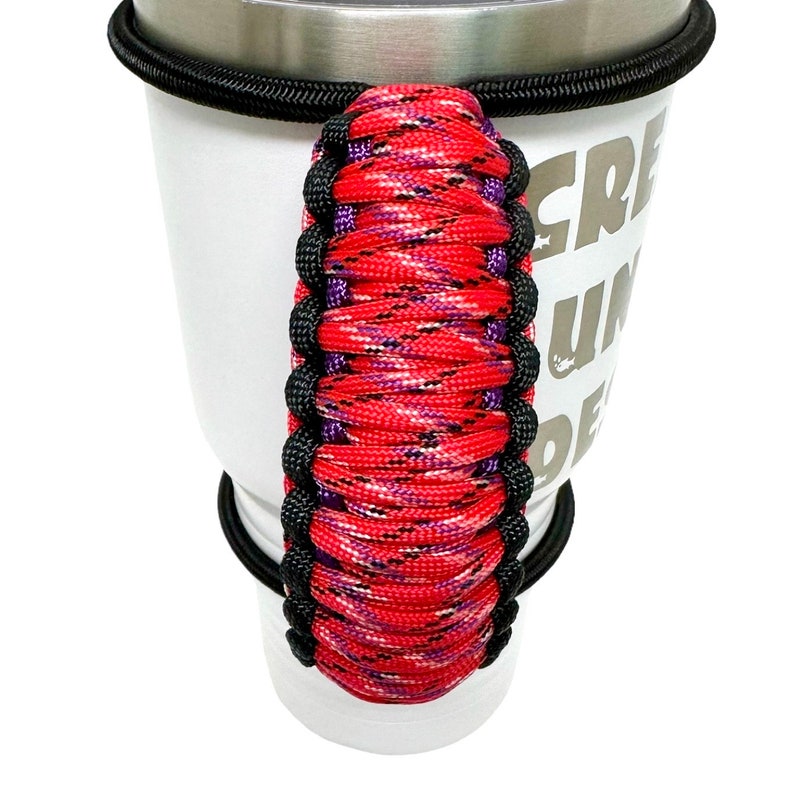 May include: Red, black, and purple paracord handle for a travel mug. The handle is wrapped in a camouflage pattern.
