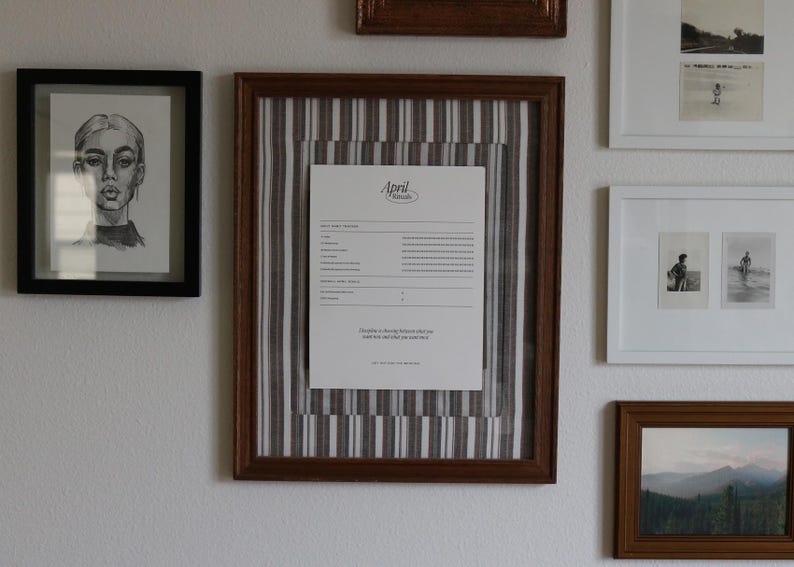 Pu&ograve; includere: Una collezione di opere d'arte incorniciate su un muro bianco. L'arte comprende un ritratto a matita, un documento con testo e schizzi di paesaggi e figure. Le cornici sono di varie dimensioni e colori, tra cui nero e marrone.