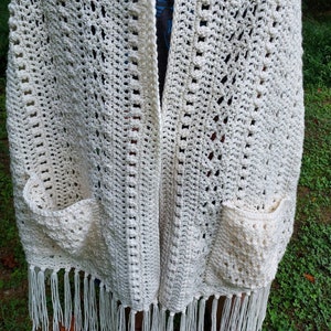 May include: White crochet shawl with fringe and two pockets.