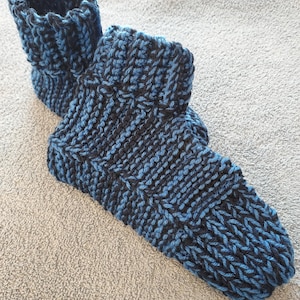 May include: A pair of blue and black knitted socks. The socks are made with a thick yarn and have a ribbed cuff.