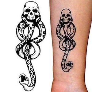May include: Black and white temporary tattoo featuring a skull atop a snake. The snake is coiled and has a patterned design. The snake's mouth is open, revealing its fangs. The tattoo is shown on a person's arm.