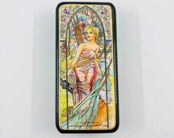 May include: A rectangular wooden box with a black border and a colorful image of a woman in a pink dress standing in a forest. The image is surrounded by a gold frame and has a floral design.