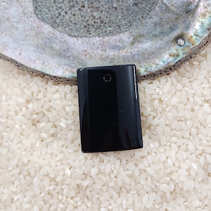 May include: A rectangular, polished black stone pendant with a smooth, reflective surface and a single small circular hole drilled near the top center. The stone has a flat, uniform appearance with sharp, clean edges and a deep, solid black color.