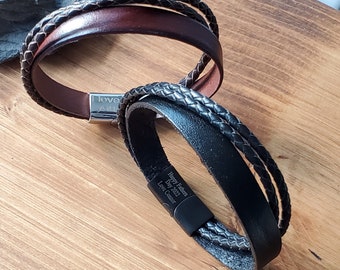 May include: Two leather bracelets with braided straps. One is brown with the inscription "I love you" and the other is black with the inscription "Happy Father's Day 2022 Love Connor".