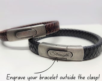 May include: Two leather bracelets with silver clasps. The clasp on the black bracelet is engraved with the word "Strength".