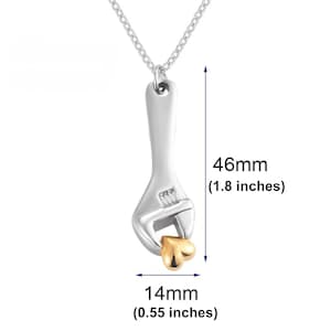 May include: Silver necklace with a wrench pendant holding a gold heart. The pendant is 1.8 inches tall and 0.55 inches wide.