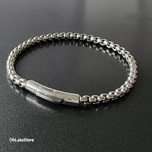 May include: A silver chain bracelet with a clasp closure. The bracelet is made of small, round links.