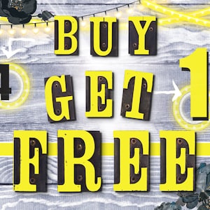 Puede incluir: Un letrero amarillo y negro con el texto "BUY 4 GET 1 FREE" sobre un fondo de madera. El letrero est&aacute; decorado con luces de cadena y flores negras.