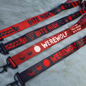 May include: Four lanyards with black and red designs. Two lanyards read "BITE RISK" with warning symbols. The other two lanyards read "WEREWOLF" and "FULL MOON BITE RISK". Each lanyard has a metal clasp.