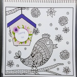 May include: A black and white coloring page featuring a bird with intricate patterns sitting on a branch. The bird is singing and there is a birdhouse with flowers and the text "Coloring Fun" in a circle in the background.