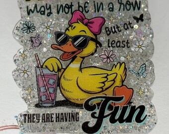 May include: A glittery badge reel with a cartoon duck wearing sunglasses and a pink bow. The text reads "MY DUCKS may not be in a row, but at least THEY ARE HAVING Fun."