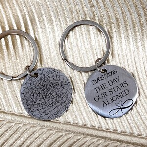 May include: Two silver keyrings with circular pendants. One pendant has a star map design, the other has the date "21/05/2025" and the text "THE DAY OUR STARS ALIGNED" with an infinity symbol.
