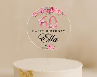 Könnte beinhalten: Runder Tortendekor mit rosa Blumen und der Zahl 60 in rosa. Der Text "Happy Birthday Ella" ist in Schwarz geschrieben.