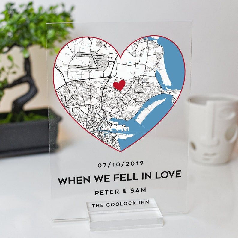May include: A clear acrylic sign with a red heart-shaped map of a city. The map shows roads, water, and a red heart marking a specific location. The text on the sign reads "07/10/2019 WHEN WE FELL IN LOVE PETER & SAM THE COOLOCK INN".