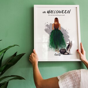 May include: A white framed print with a green and black illustration of a woman in a green dress and black shoes. The text on the print reads "on HALLOWEEN you can be anything you want." and "Emily".