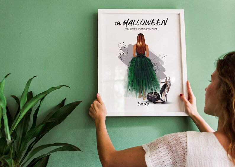 May include: A white framed print with a green and black illustration of a woman in a green dress and black shoes. The text on the print reads "on HALLOWEEN you can be anything you want." and "Emily".