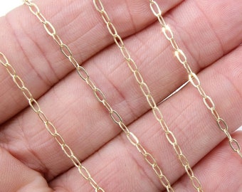 May include: A gold chain necklace with a delicate, oval-shaped link design. The chain is shown on a hand, with the ends of the chain hanging down.