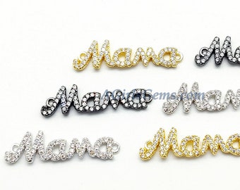 Puede incluir: Cinco dijes de metal de diferentes colores con la palabra "Mama" escrita en brillantes diamantes de imitación. Los dijes son de oro, plata, negro y dos tonos de oro.