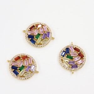 May include: Three gold-toned round charms with a circle of clear rhinestones around the edge. Each charm has a different arrangement of colorful rectangular stones in shades of pink, blue, green, and red.