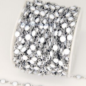 May include: A spool of white and silver chain with round, white beads. The chain is made of metal and is perfect for jewelry making.