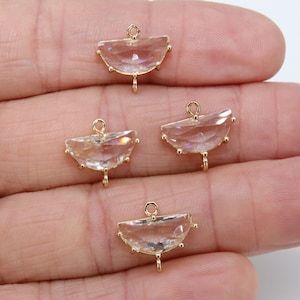 May include: Four gold-tone metal charms with clear faceted glass stones. Each charm has a loop at the top for attaching to jewelry.