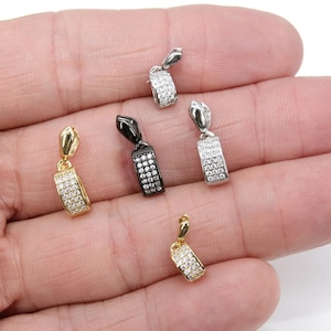 Op de afbeelding: Vijf verschillende hangerbedels met een zilveren, gouden en zwarte afwerking. Elke bedel heeft een rechthoekige vorm met een rij heldere zirkonia-stenen.