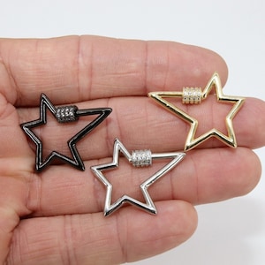May include: Three star-shaped metal clasps with clear crystal accents. The clasps are in black, silver, and gold.