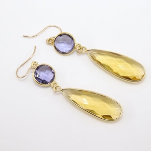 May include: Gold earrings with a teardrop-shaped yellow gemstone and a round purple gemstone.