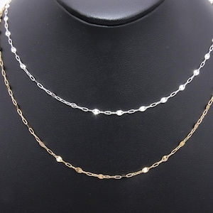 May include: Two delicate chain necklaces, one gold and one silver, with small, flat, oval-shaped links. The necklaces are displayed on a black mannequin bust.