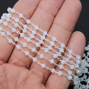 May include: A strand of white opal beads strung on a silver chain. The beads are faceted and have a subtle shimmer.