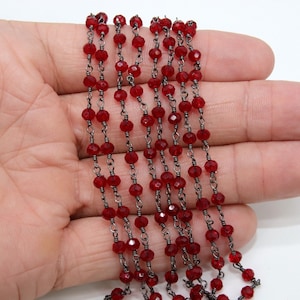 May include: A strand of red faceted glass beads strung on a silver chain. The beads are small and round, and the chain is delicate.