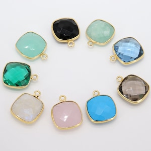 May include: Assortment of ten gemstone pendants with gold-toned settings. The pendants are square-shaped and feature various colors, including green, blue, pink, black, and white.
