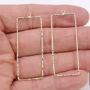 May include: Two gold-toned metal rectangular frames with a hammered texture. The frames have a loop at the top for hanging.