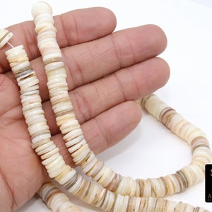 以下が含まれることがあります： 白と茶色の貝殻ビーズのネックレス。自然な虹色の光沢があります。ビーズは積み重ねられ、円形に配置されており、ユニークで質感のある外観になっています。