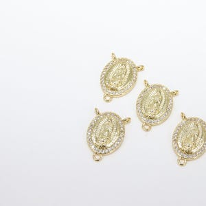 May include: Four gold-tone oval charms with a raised image of the Virgin Mary and clear rhinestones. Each charm has a jump ring for attaching to a necklace or bracelet.