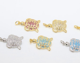 May include: Six gold-tone turtle charms with different colored crystal accents. The charms are set with clear, blue, pink, and dark blue crystals.