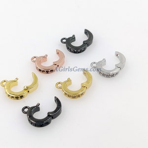 Könnte beinhalten: Fünf verschiedene farbige Metallverschlüsse mit einer Reihe von klaren Zirkonia-Steinen. Die Verschlüsse sind in Schwarz, Gold, Silber, Roségold und Gunmetal.