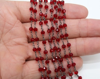 May include: A strand of red faceted glass beads strung on a silver chain. The beads are small and round, and the chain is delicate.