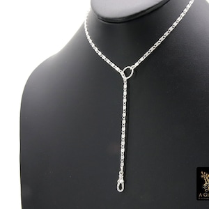 May include: A silver chain necklace with a small circle pendant and a silver clasp. The necklace is displayed on a black mannequin.