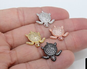 May include: Four turtle charms with cubic zirconia stones and red accents. The turtles are in silver, gold, rose gold, and black.